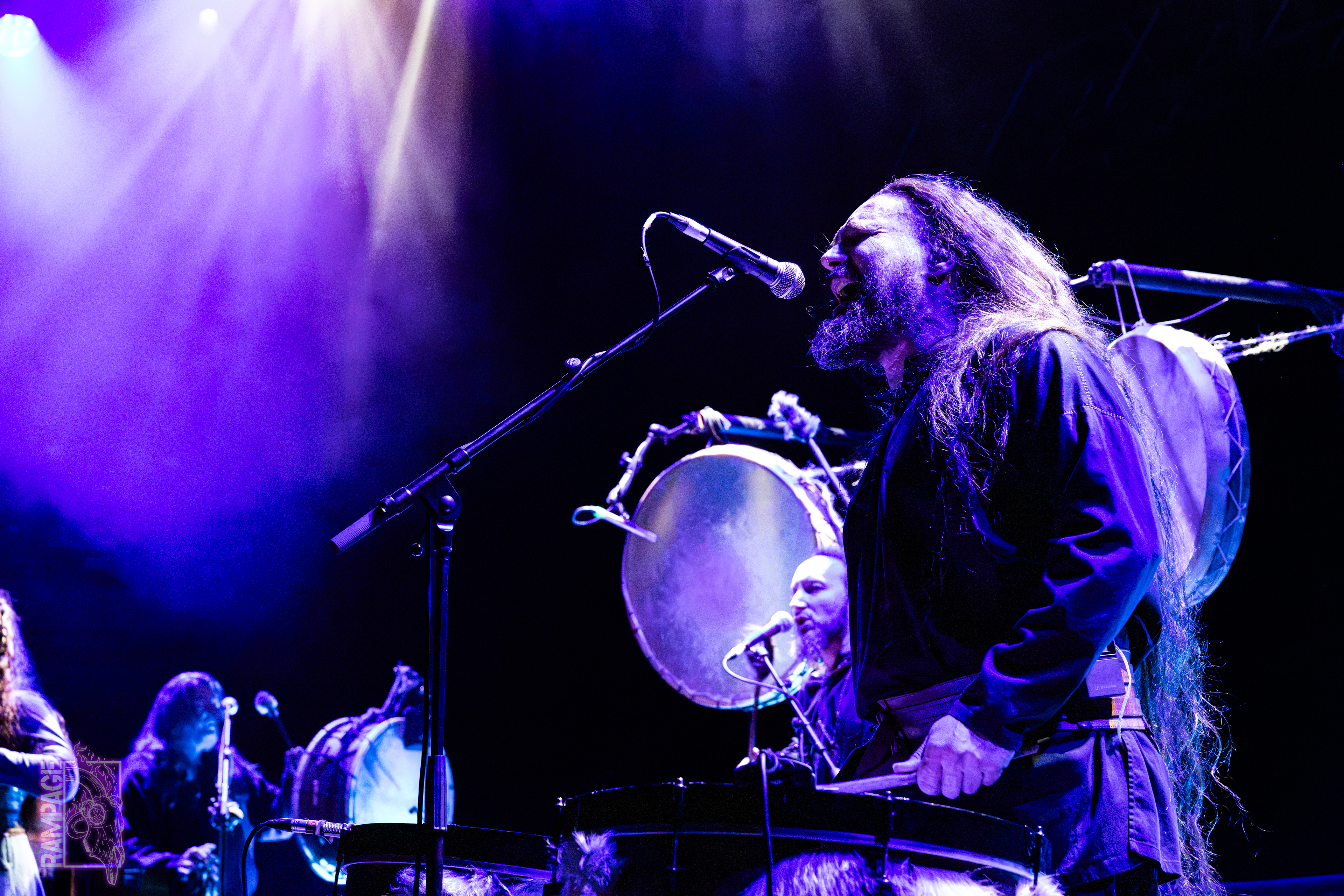 Members of Neo-folk band Skald bathed in blue light. They're playing drums and singing into microphones